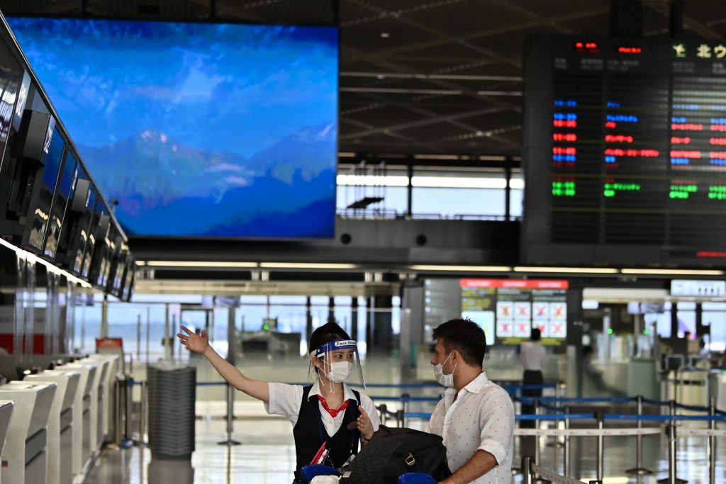 An airline employee wearing a face shield talks with a passenger at the Narita International Airport in Narita, Chiba Prefecture on August 19, 2020. (AFP)