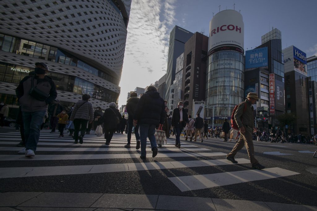 People cross a street in the Ginza shopping district in Tokyo on December 6, 2020. (AFP)