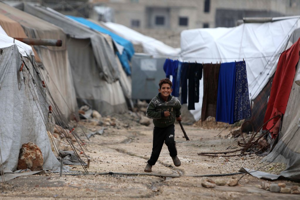 A Syrian child runs among shelters at a camp for displaced Syrians near the town of Kafr Lusin by the border with Turkey, in Syria's rebel-held northwestern province of Idlib on December 15, 2020. (AFP)