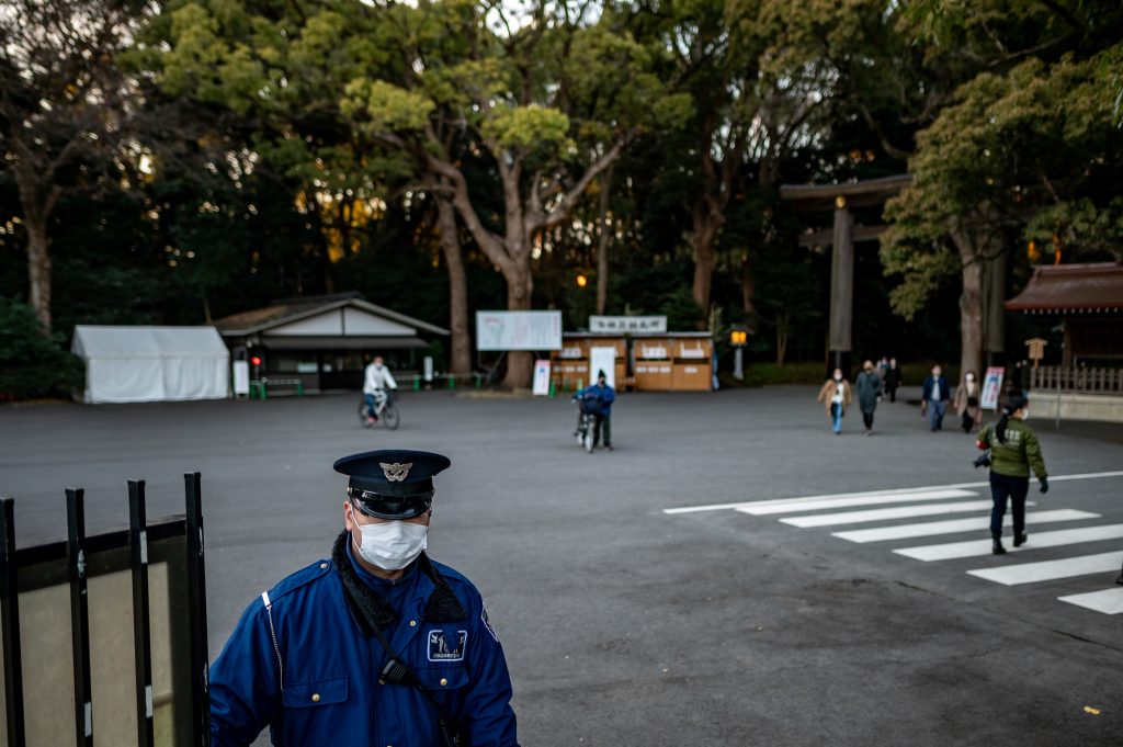 A security guard closes a gate to Meiji Shrine as it closes early on New Year's Eve in Tokyo on December 31, 2020. (Photo by Philip FONG / AFP)