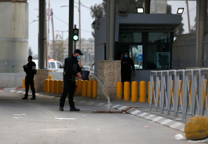 An Isaeli soldier cleans the blood stains at the spot where a Palestinian suspected of attacking troops was shot and wounded at the Qalandia checkpoint on the crossing between the West Bank city of Ramallah and Israeli-annexed east Jerusalemon on December 7, 2020. (AFP)