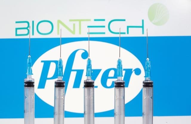 Syringes are seen in front of displayed Biontech and Pfizer logos in this illustration taken November 10, 2020. (Reuters)