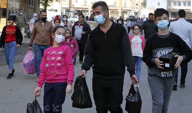 Iraqis wearing facemasks amid the Covid-19 pandemic, walk with their shopping in the capital Baghdad, on December 4, 2020. (AFP)