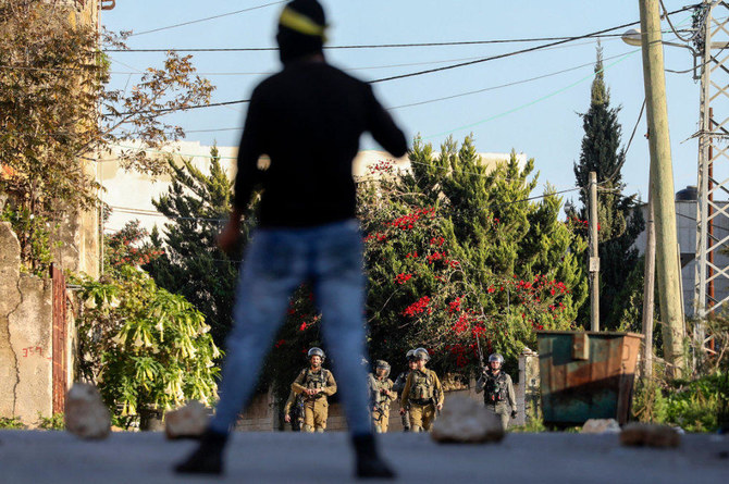 A Palestinian protester confronts Israeli troops during clashes following a demonstration against the expropriation of Palestinian land by Israel, in the village of Kfar Qaddum near the Jewish settlement of Qadumim (Kedumim), in the Israeli-occupied West Bank, on December 19, 2020. (AFP / JAAFAR ASHTIYEH)