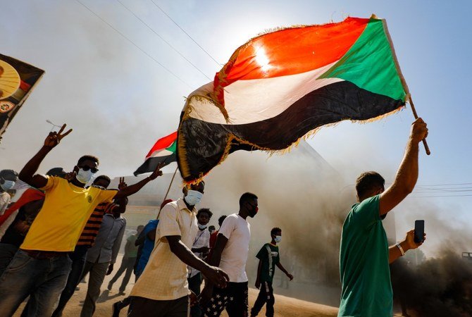 Sudanese youths wave the national flag as they rally in the streets of the capital Khartoum, chanting slogans and burning tires, to mark the second anniversary of the start of a revolt that toppled the previous government on Dec. 19, 2020. (File/AFP)