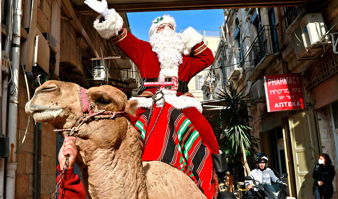 Issa Kassissieh, better known as the Santa Claus of Jerusalem, rides a camel inside Jerusalem’s Old City on Tuesday. The region will celebrate a quiet Christmas this year because of the pandemic. (AFP)