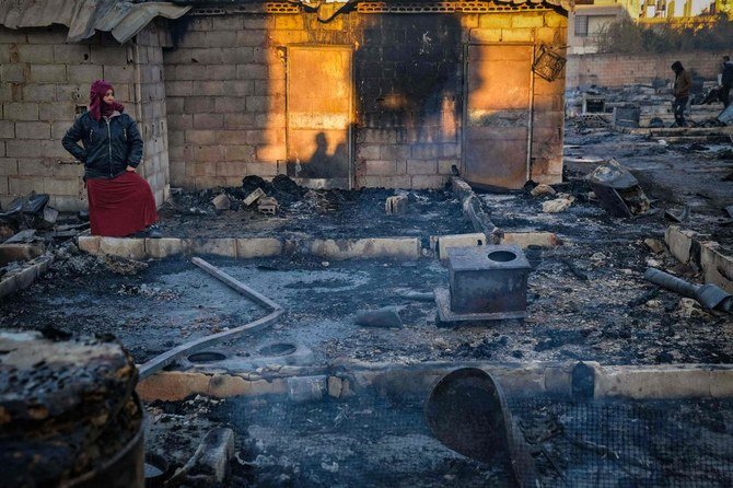 Syrian refugees salvage belongings from the wreckage of their shelters at a camp set on fire overnight in the northern Lebanese town of Bhanine on December 27, 2020, following a fight between members of the camp and a local Lebanese family. (AFP)