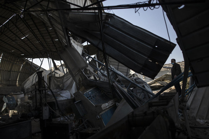 A Palestinian man wearing a face mask inspects a damaged plastic workshop following Israeli airstrikes on Gaza City, Saturday, Dec. 26, 2020. (AP Photo/Khalil Hamra)