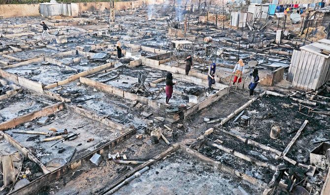 Syrian refugees salvage belongings from the wreckage of their shelters at a camp set on fire overnight in the northern Lebanese town of Bhanine on December 27, 2020, following a fight between members of the camp and a local Lebanese family. (AFP)