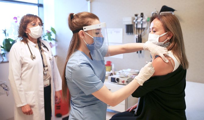 In this Monday, Dec. 21, 2020 file photo, under the watchful eye of Prof. Dr. Iftahar Koksal, left, nurse Arzu Yildirim, center, administers a dose of the CoronaVac vaccine, made by Sinovac, currently on phase III clinical trials at Acibadem Hospital in Istanbul. (AP)