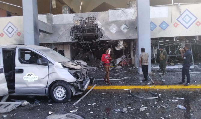 Bystanders and a soldier stand near a damaged portion of the airport of Yemen’s southern city of Aden after an explosion, Wednesday, Dec. 30, 2020. (AP)