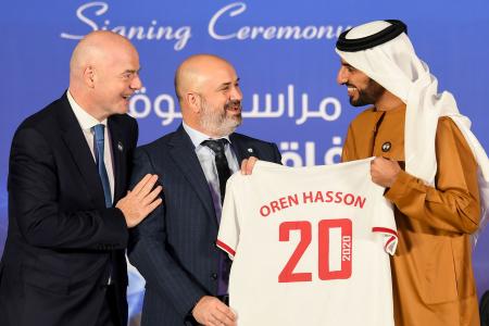 FIFA President Gianni Infantino (left) reacts as Israeli Football Association (IFA) president Oren Hasson (centre), receives a jersey from UAE Football Association (UAEFA) president Sheikh Rashid bin Humaid Al Nuaimi, after the signing of a memorandum of understanding (MoU) between the two associations in Dubai, on December 14, 2020. (AFP)