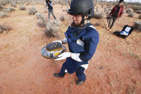 In this photo a member of JAXA retrieves a capsule dropped by Hayabusa2 in Woomera, southern Australia, Sunday, Dec. 6, 2020. The Japanese capsule carrying the first samples of asteroid subsurface shot across the night atmosphere early Sunday before successfully landing in the remote Australian Outback, completing a mission to provide clues to the origin of the solar system and life on Earth. (AP)