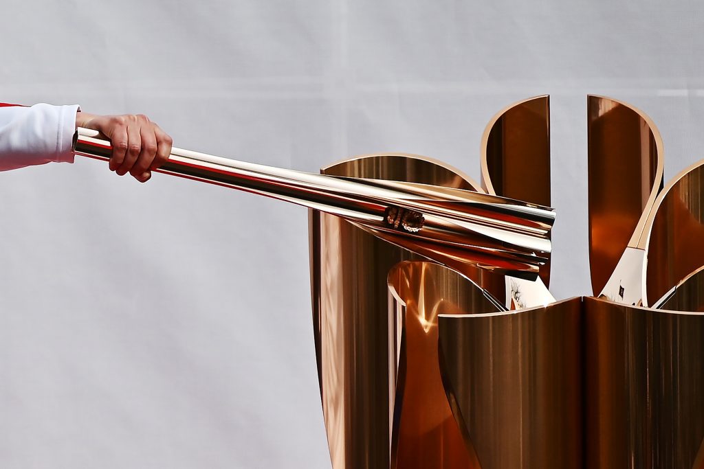 A runner holding an Olympic torch practices lighting a cauldron during a rehearsal of the Tokyo 2020 Olympics torch relay in Tokyo on February 15, 2020. (AFP)