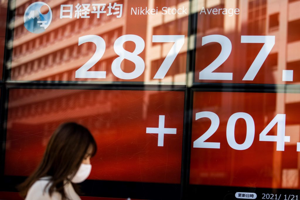 Pedestrians walks past a stock indicator displaying numbers of Nikkei 225 of the Tokyo Stock Exchange in Tokyo on Jan. 21, 2021. (AFP)