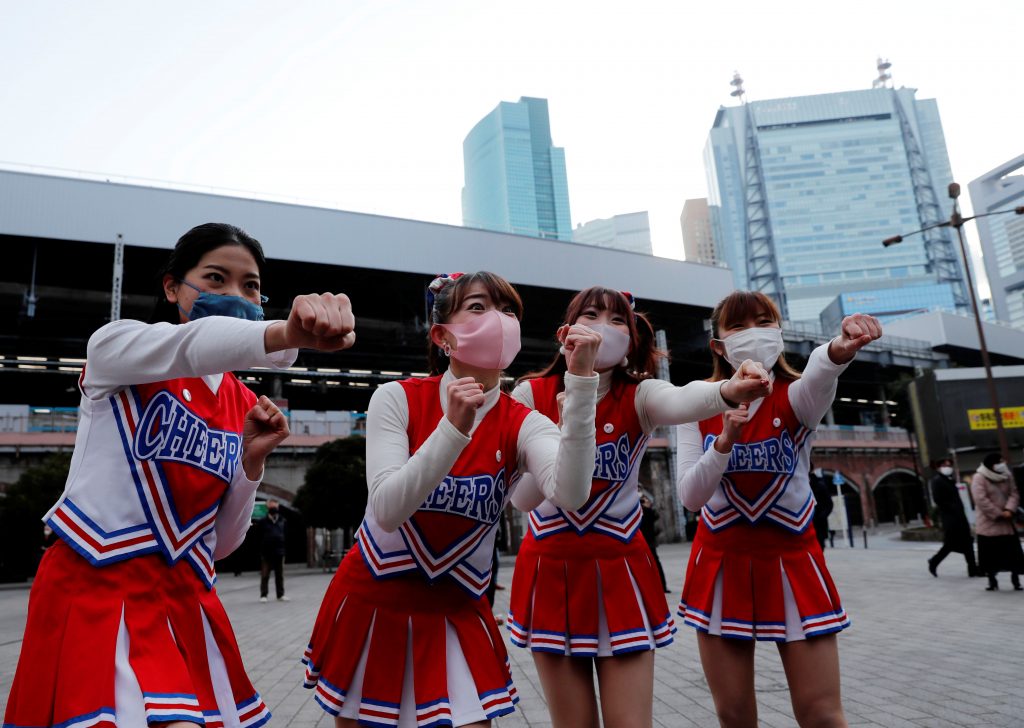 Cheerleaders wearing protective face shields, amid the coronavirus disease (COVID-19) outbreak, cheer people up in front of Shimbashi Station during the commuting hour in Tokyo, Japan, January 7, 2021. (Reuters)
