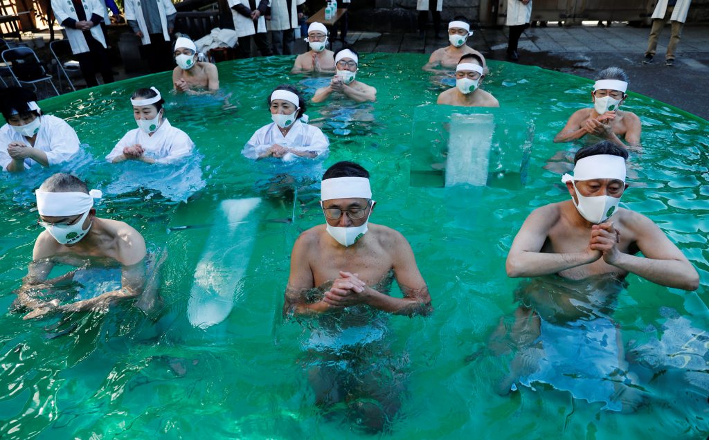 Participants wearing protective face masks amid the coronavirus disease (COVID-19) outbreak, pray as they take an ice-cold bath during a ceremony to purify their souls and to wish for overcoming the pandemic at the Teppozu Inari shrine in Tokyo, Japan, January 10, 2021. REUTERS/Kim Kyung-Hoon