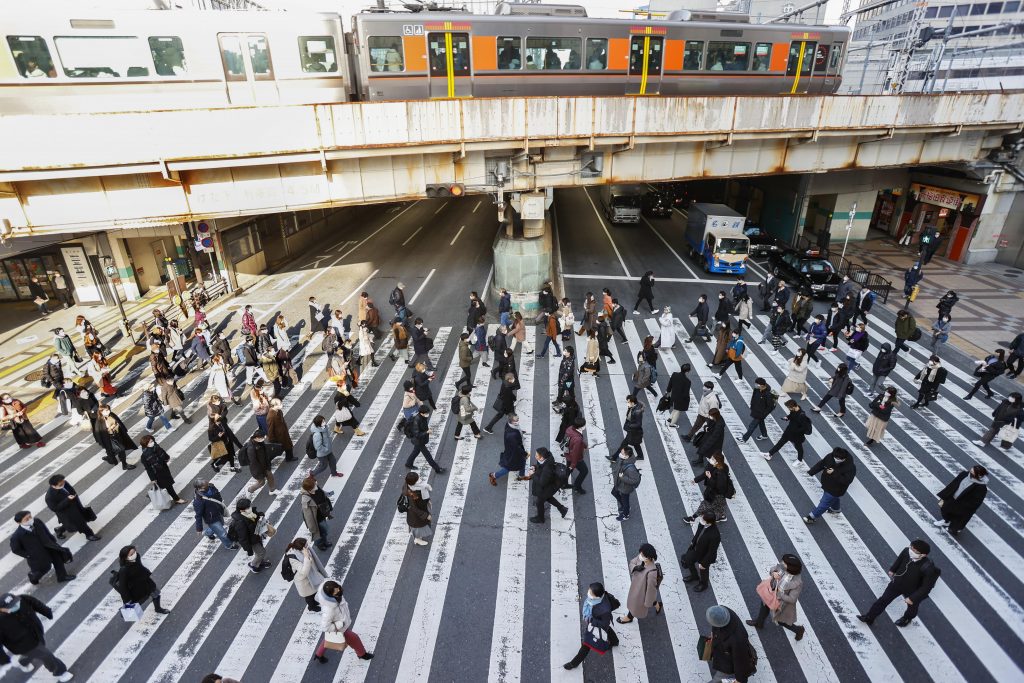 People wear face masks as they walk on a street in Osaka, western Japan Thursday, Jan. 14, 2021. Japan expanded a coronavirus state of emergency to seven more prefectures, affecting more than half the population amid a surge in infections across the country. (Yosuke Mizuno/Kyodo News via AP)