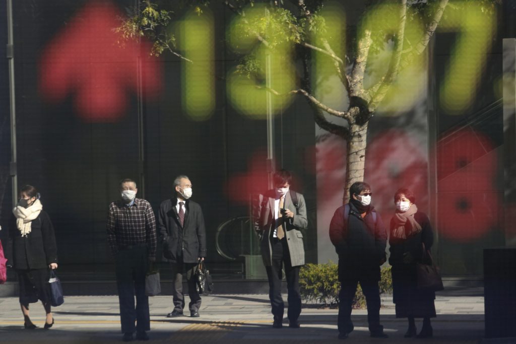 People are reflected on the electronic board of a securities firm in Tokyo, Wednesday, Jan. 20, 2021. Asian shares were mostly higher Wednesday, ahead of Joe Biden's inauguration as president, ending President Donald Trump's four-year term. Japan's benchmark lost early gains as worries grew about the surge in coronavirus cases. (AP Photo/Koji Sasahara)