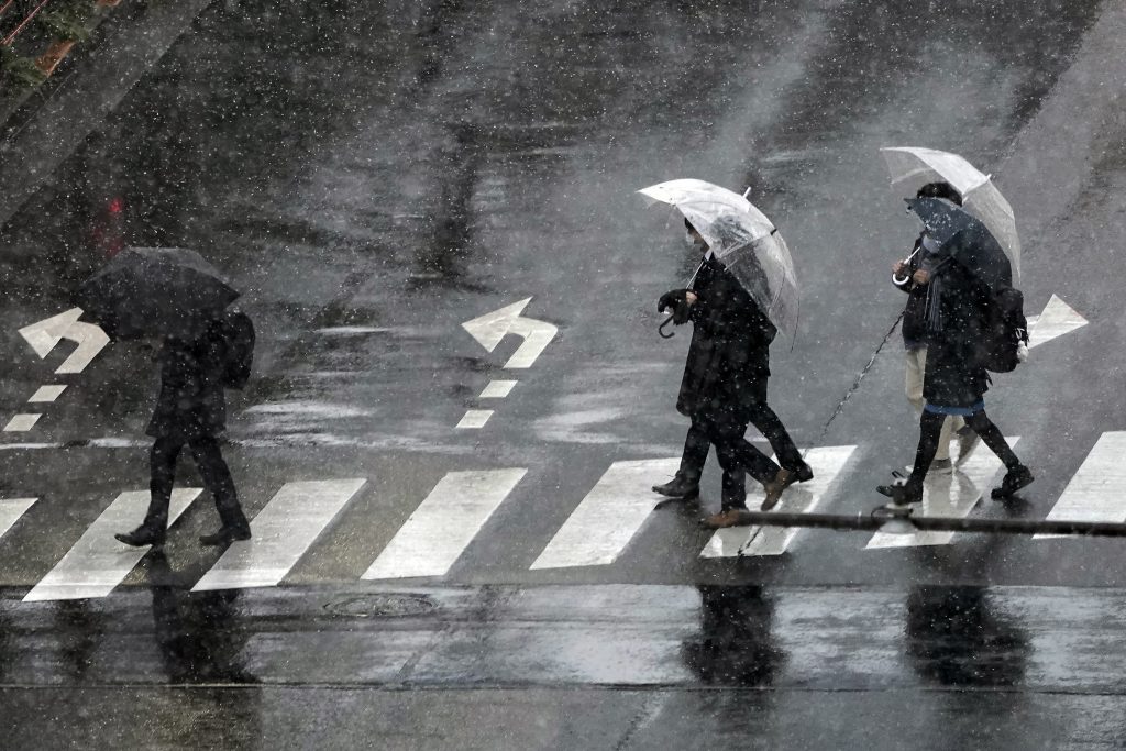 People wearing protective masks to help curb the spread of the coronavirus walk on a pedestrian crossing in the snow, in Tokyo, Jan. 28, 2021. (File photo/AP)