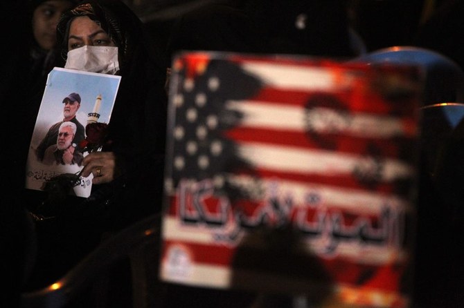 An Iraqi woman carries a portrait of late Iraqi commander Abu Mahdi Al-Muhandis and Iranian commander Qasem Soleimani at Baghdad Airport, in Baghdad on January 2, 2021, at the site of their killing. (AFP)