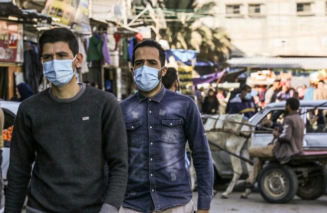 Palestinian men wear protective face masks in Rafah in the southern in Gaza Strip on Dec.10, 2020, as cases of infections with the coronavirus surge in the coastal enclave. (File/AFP)