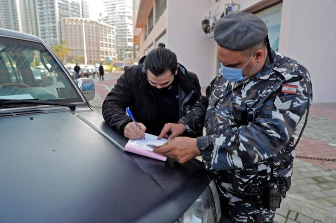 A policeman books a driver for having violated the lockdown imposed by the authorities in a bid to slow the spread of the coronavirus, in the town of Antelias, east of the Lebanese capital Beirut, on January 7, 2021. (AFP)