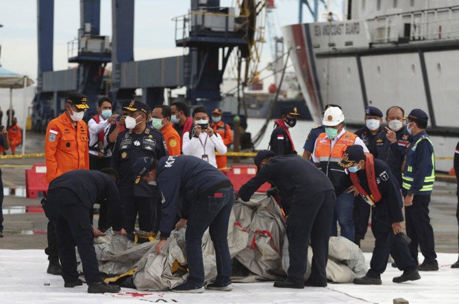 Investigators at the search and rescue command center in Tanjung Priok Port, Jakarta on Sunday inspect debris found in the waters around the location where a Sriwijaya Air passenger jet has lost contact with air traffic controllers shortly after the takeoff on Jan. 9, 2021. (AP Photo/Achmad Ibrahim)