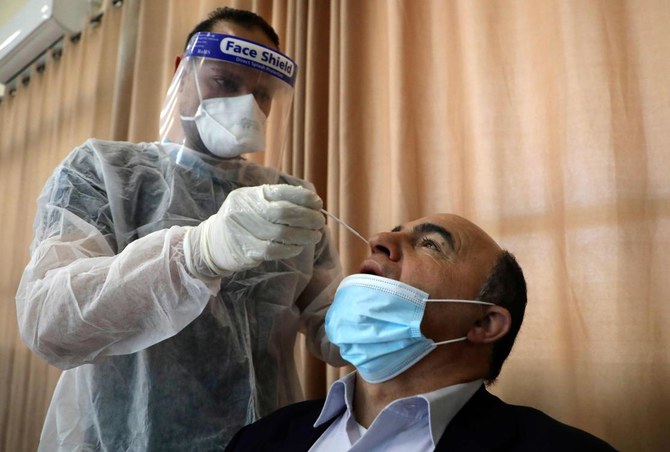 A Palestinian health worker takes a swab sample from a man to test for COVID-19 coronavirus in the West Bank village of Dura, southwest of Hebron, on January 8, 2021. (AFP)