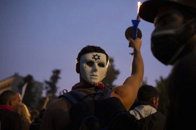 Above, an Israeli anti-government protester wears a mask on the back of his head outside of the official residence of Prime Minister Benjamin Netanyahu on Jan. 13, 2021. (AP)