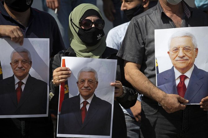 In this Sept. 27, 2020 file photo, Palestinians wearing protective face masks amid the coronavirus pandemic, hold pictures of Palestinian President Mahmoud Abbas during a rally to support Abbas, in the West Bank town of Tubas.(AP)