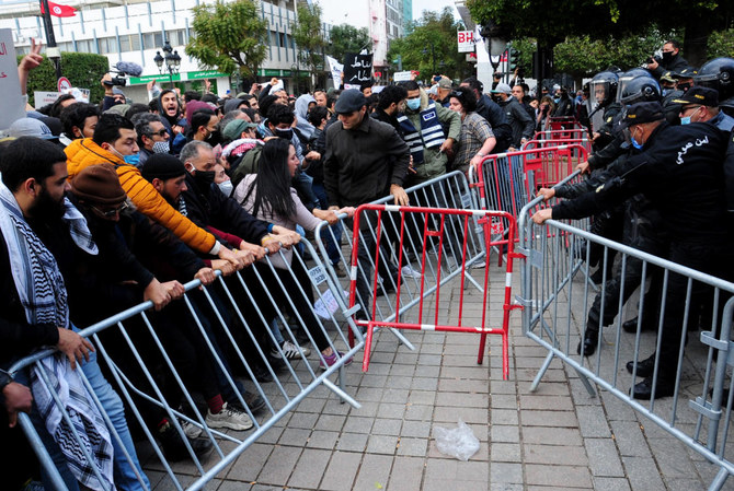 Demonstrators face police officers during a demonstration in Tunis, Saturday, Jan.23, 2021. (AP)