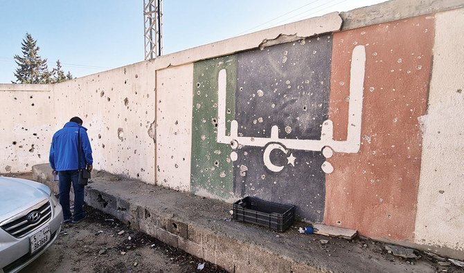 In this file photo taken on November 19, 2020, a Libyan stands in front of a school, which was damaged during fighting between rival factions, in the capital Tripoli's suburb of Ain Zara. (AFP)