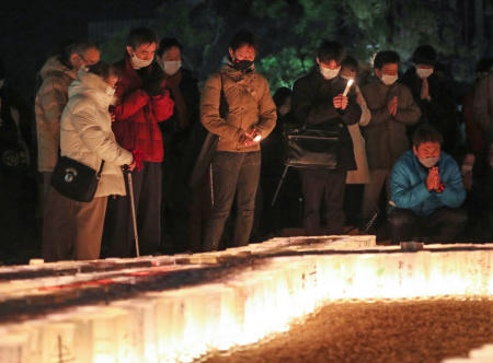 People pray for victims around candles commemorating the 26th anniversary of the Great Hanshin Earthquake at a park in Kobe, Hyogo prefecture on January 17, 2021. (AFP)