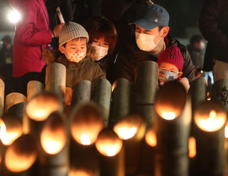 People pray for victims around candles commemorating the 26th anniversary of the Great Hanshin Earthquake at a park in Kobe, Hyogo prefecture on January 17, 2021. (AFP)