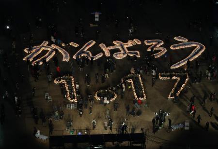 People gather around candles forming characters meaning