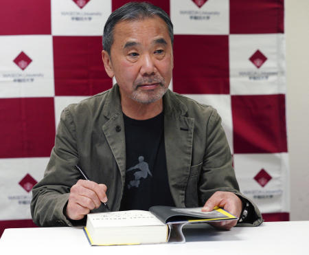In this Nov. 3, 2018, file photo, Japanese novelist Haruki Murakami signs his autograph on his novel 