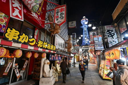 Pedestrians wearing protective face masks walk on a nearly empty street at the Shinsekai shopping and amusement district, amid the coronavirus disease (COVID-19) outbreak, in Osaka, Tuesday. (Reuters)