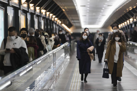 People wearing face masks to prevent the spread of coronavirus walk towards a train station in the evening in Tokyo on Friday, Jan. 22, 2021. (AP)