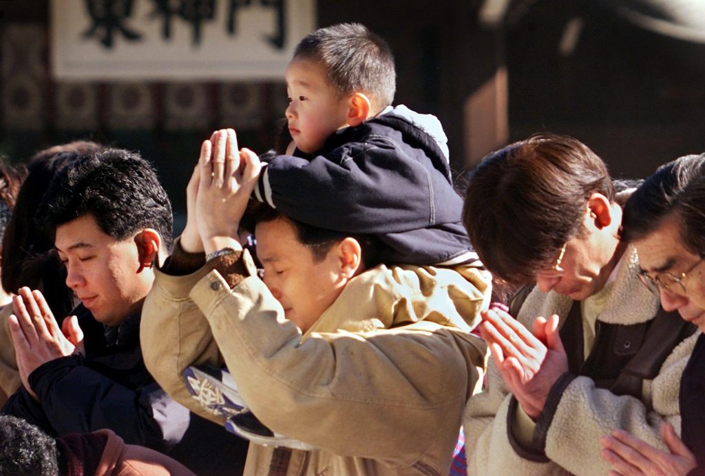 A man carries a boy on his shoulders as they pray for health and happiness before the altar at the Meiji-Jingu Shrine in central Tokyo. (AFP/file)