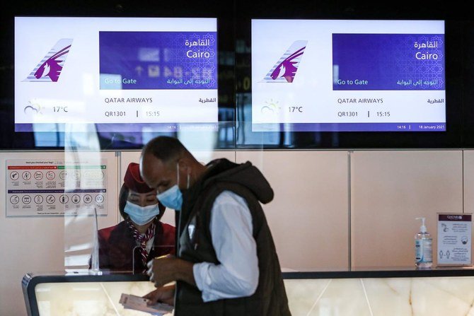 A mask-clad traveller prepares to board the first Qatar Airways flight bound for Cairo after the resumption of flights between Qatar and Egypt, at Qatar's Hamad International Airport near the capital Doha on January 18, 2021. Egypt reopened its airspace to Qatari flights on January 18 following a thaw in relations between Doha and a Saudi-led bloc. (AFP)