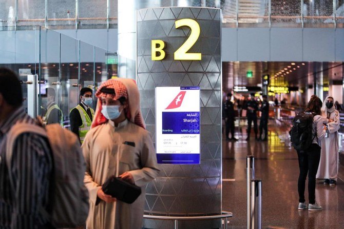 Mask-clad travellers wait at the gate before boarding the first flight to Sharjah after the resumption of air travel between Qatar and the United Arab Emirates, at Qatar's Hamad International Airport on January 18, 2021. (AFP)