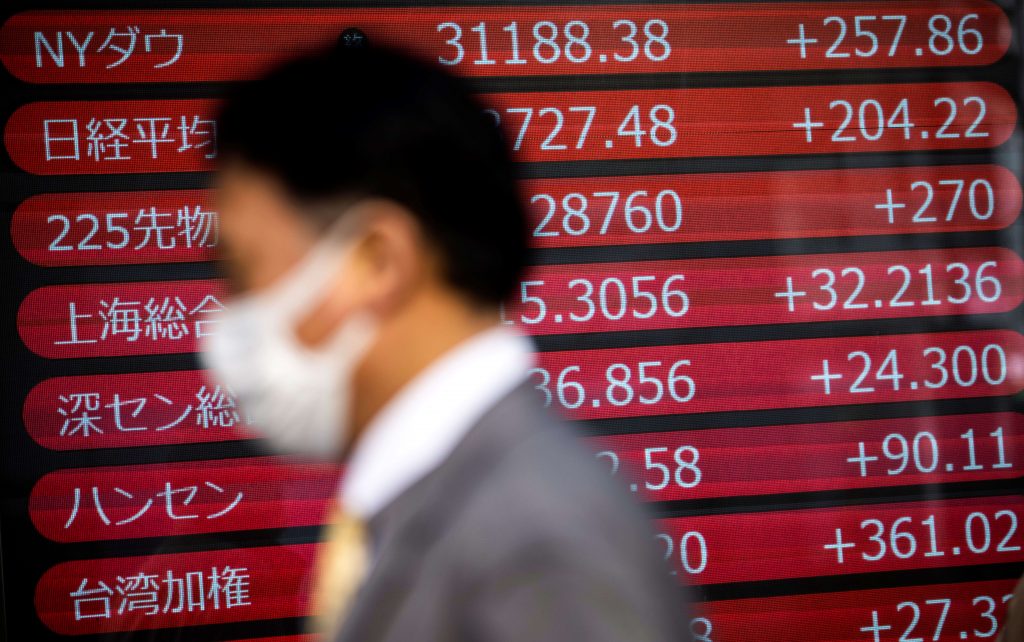 A pedestrian walks past an electronic quotation board displaying world share prices in Tokyo on January 21, 2021. (AFP)
