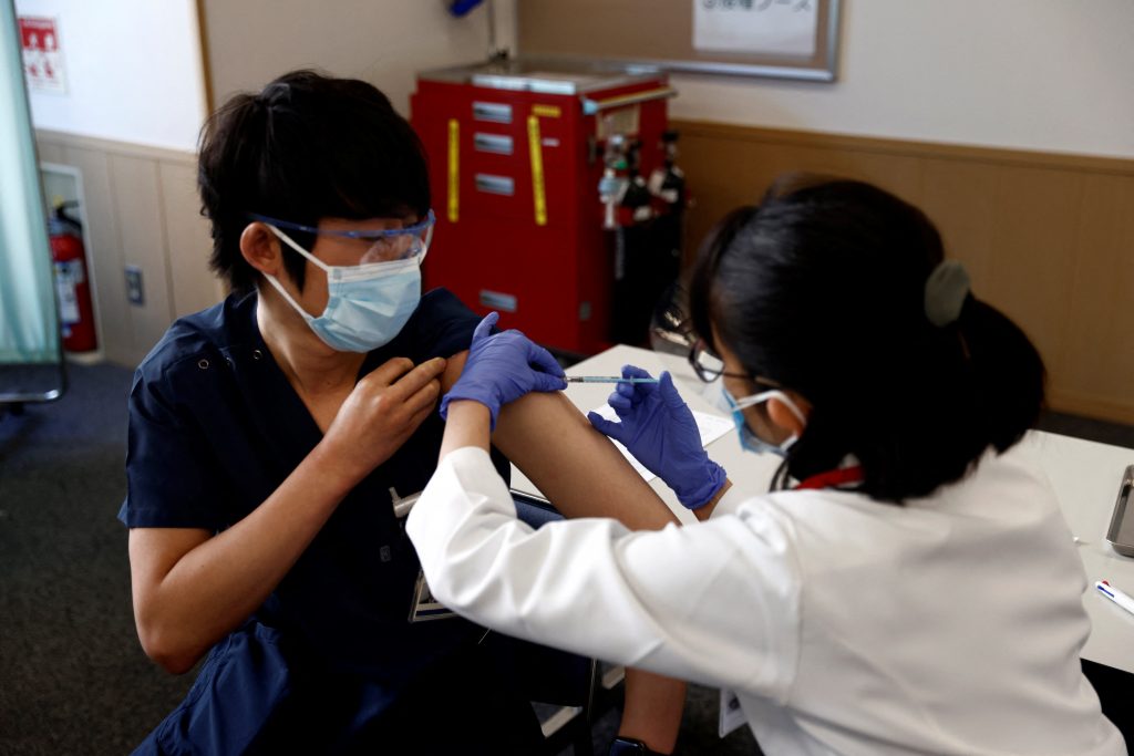 A medical worker (L) receives a dose of the COVID-19 vaccine as the country launches its inoculation campaign at the Tokyo Medical Center in Tokyo on February 17, 2021. (AFP)