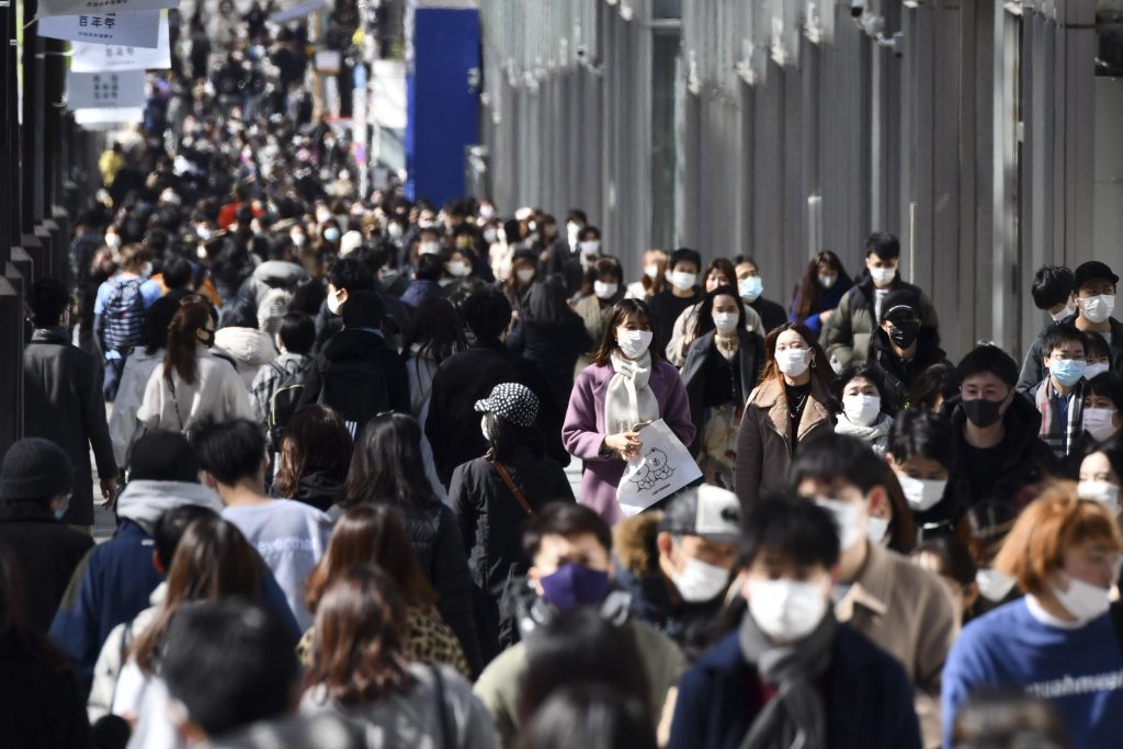 People wearing face masks walk along a street in the Harajuku shopping district in Tokyo,  Feb. 27, 2021. (AFP)