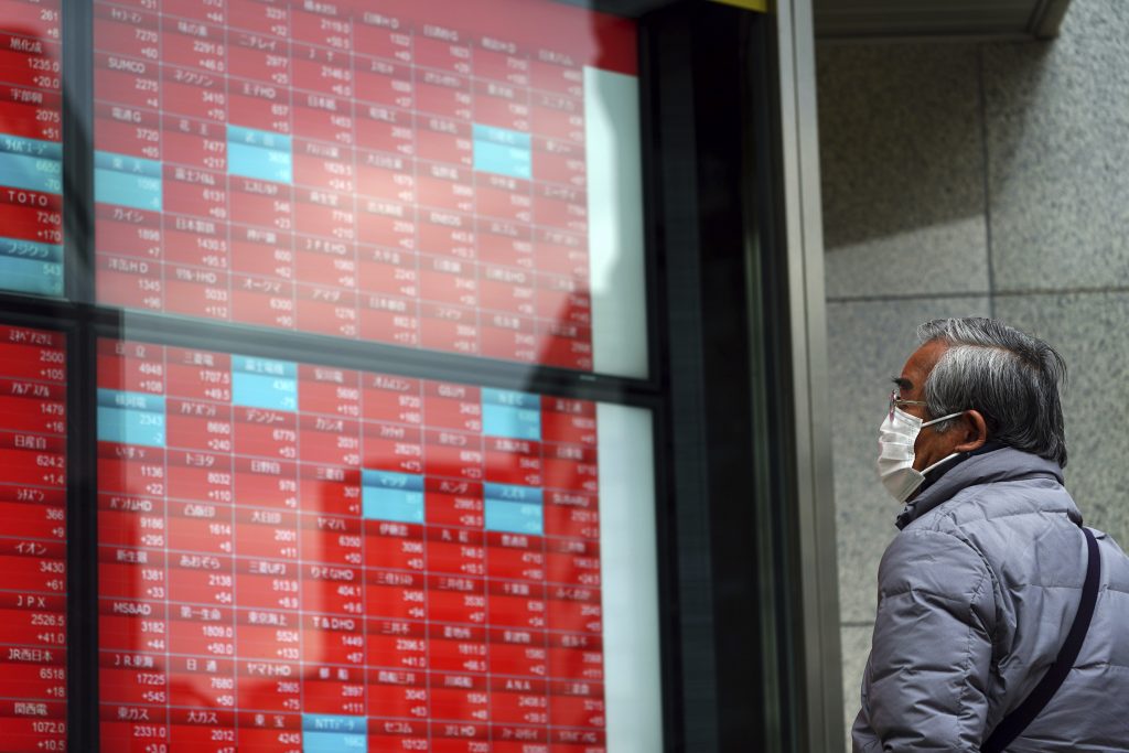 A man wearing a protective mask to help curb the spread of the coronavirus looks at an electronic stock board showing Japan's Nikkei 225 index at a securities firm, Feb. 8, 2021. (File photo/AP)