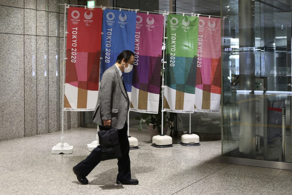 A man wearing a face mask walks past banners to promote the Tokyo Olympics, in Tokyo, Wednesday, Feb. 17, 2021. The Olympics are scheduled to open on July 23 but recent polls show about 80% of the Japanese public want the Olympics canceled or postponed. Gov. Tatsuya Maruyama of Shimane prefecture, western Japanese, is talking about canceling the torch relay events in his area for the Tokyo Games, reported on Wednesday. Maruyama is unhappy with COVID-19 prevention measures surrounding the relay. (AP Photo/Koji Sasahara)