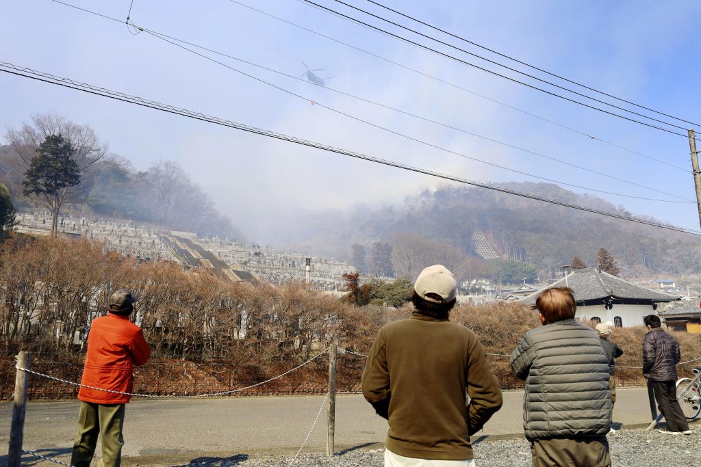 A helicopter dumps water on a wildfire in Ashikaga, Tochigi prefecture, north of Tokyo Wednesday, Feb. 24, 2021. (File photo/Kyodo News via AP)