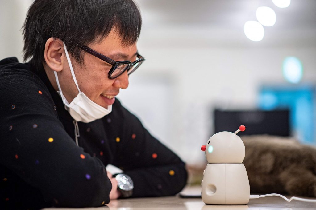 In this picture taken on December 8, 2020 shows Shunsuke Aoki, CEO of Yukai Engineering talking with the robot Bocco emo in a studio in Tokyo. Smart home assistants like Amazon's Alexa have found success worldwide, but tech firms in Japan are reporting huge demand for more humanlike alternatives, as people seek solace during virus isolation. (AFP)