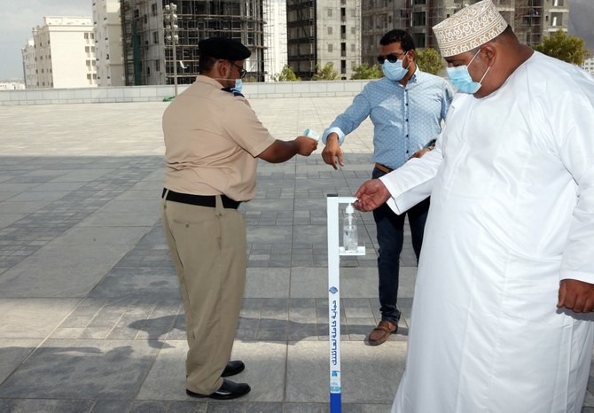 Mask-clad men use disinfecting gel and get their temperature checked before entering the Mohammed al-Amin Mosque in the Omani capital Muscat on Nov. 15, 2020. (File/AFP).